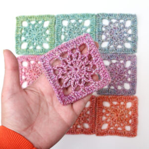 Simple Crochet Square made with pink and purple variegated yarn, held in hand